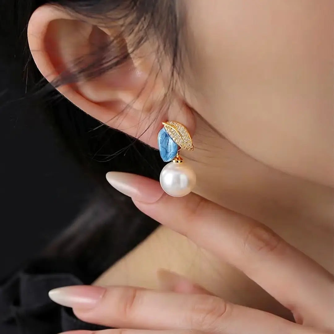 Woman touching her earlobe wearing the Aiko Tanaka Soka blue flower and white pearl drop earring