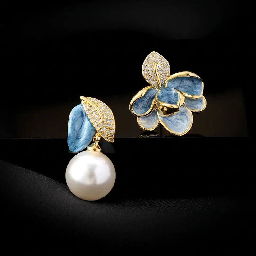 Aiko Tanaka Soka earrings with blue enamel flower petals, gold crystal leaves and a large white pearl on black