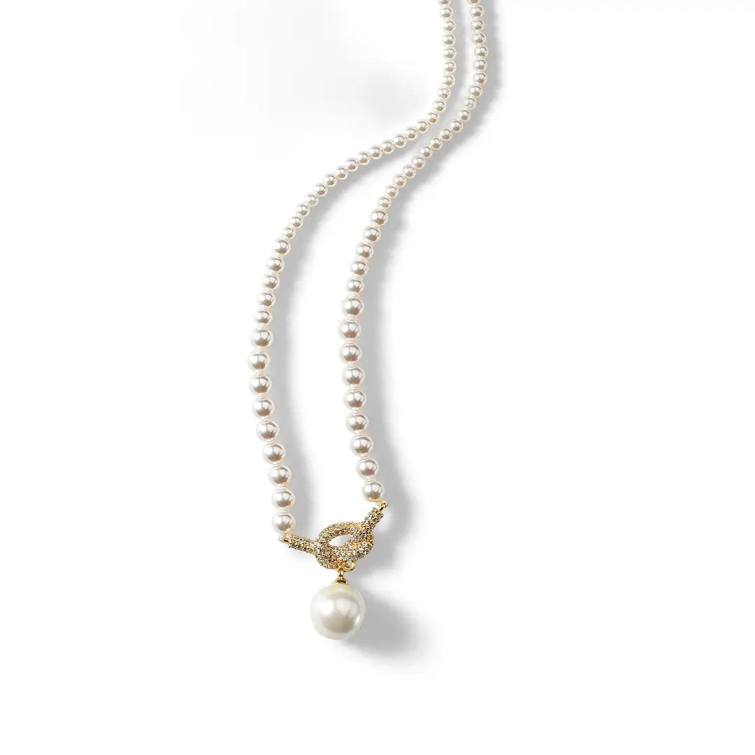 Aiko Tanaka white pearl necklace with a gold toggle clasp and a single large pearl drop, on a white background
