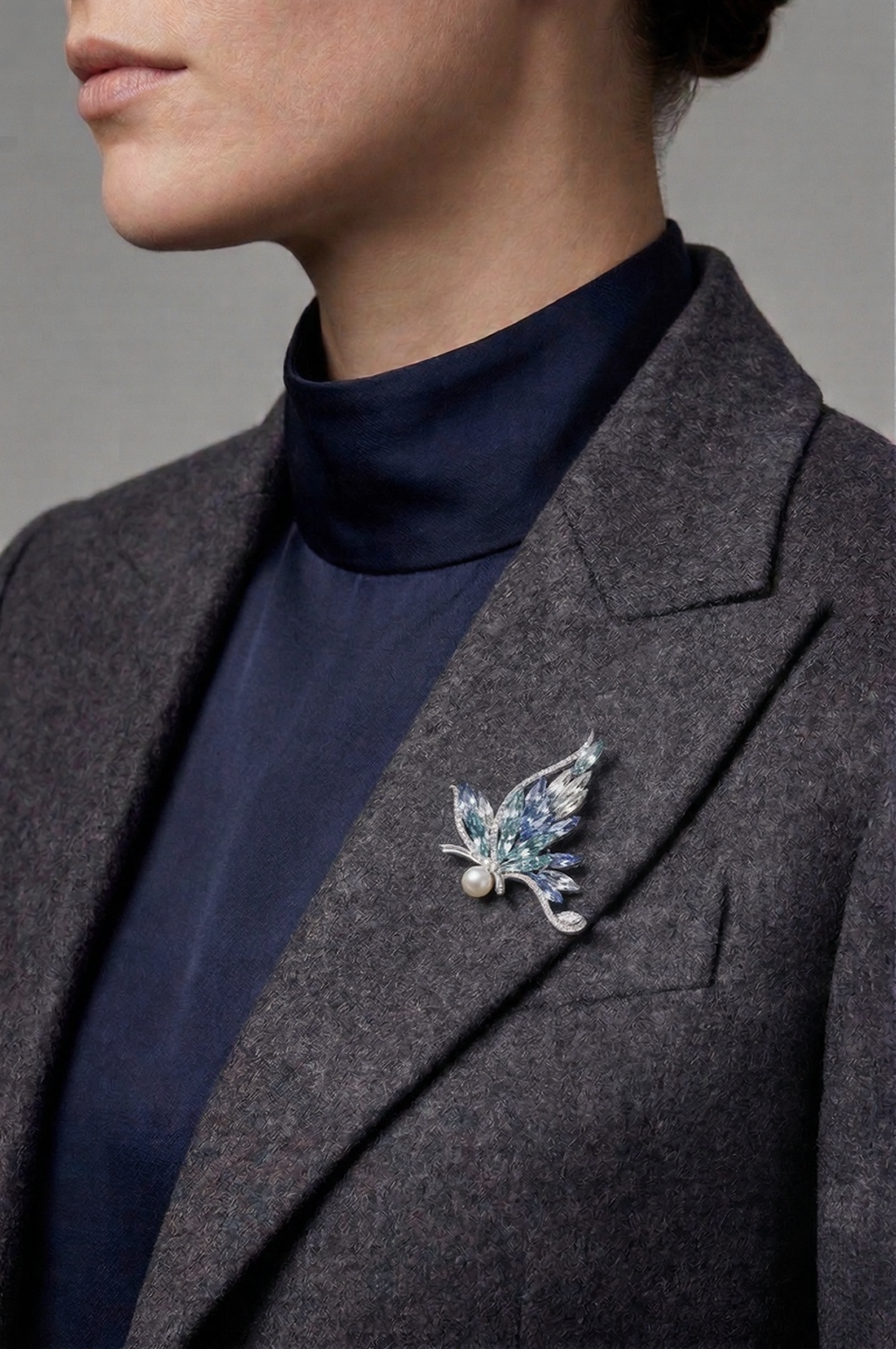 Woman in a grey wool blazer wearing the Aiko Tanaka Ao no Senko blue crystal and pearl brooch on her lapel