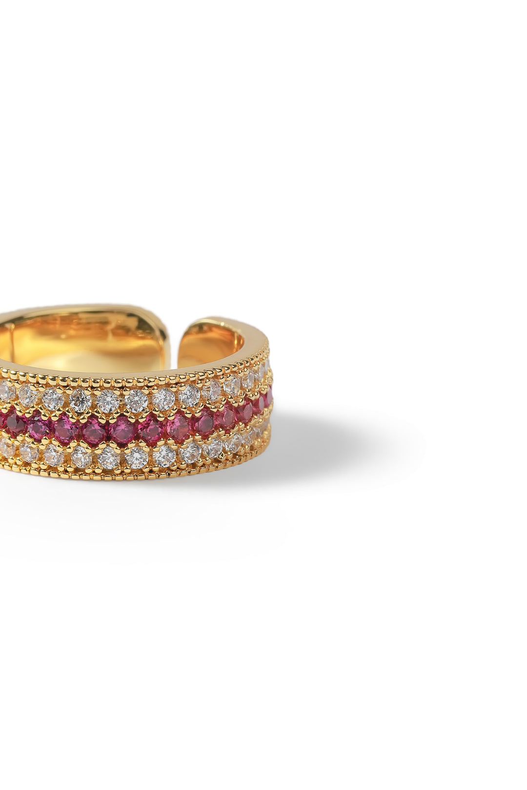 Aiko Tanaka Kiseki ring, a wide gold band set with rows of pink stones and white crystals, on a white background