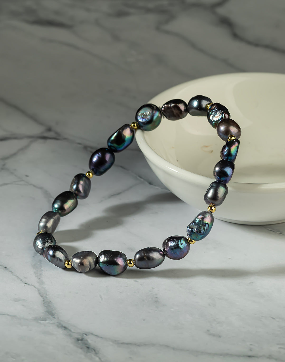 Aiko Tanaka Yoru no Shizuku black baroque pearl bracelet draped against a white bowl on a grey marble surface