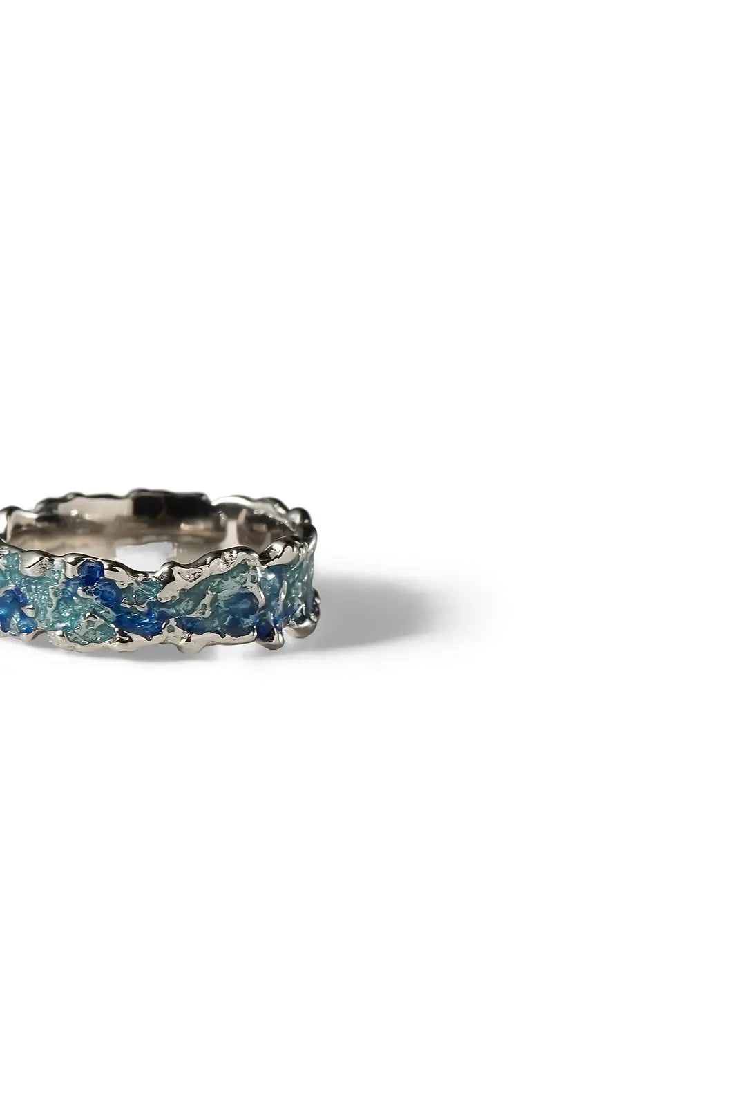 Aiko Tanaka Awanami ring, a silver band textured with blue enamel waves and sparkling stones, on a white background