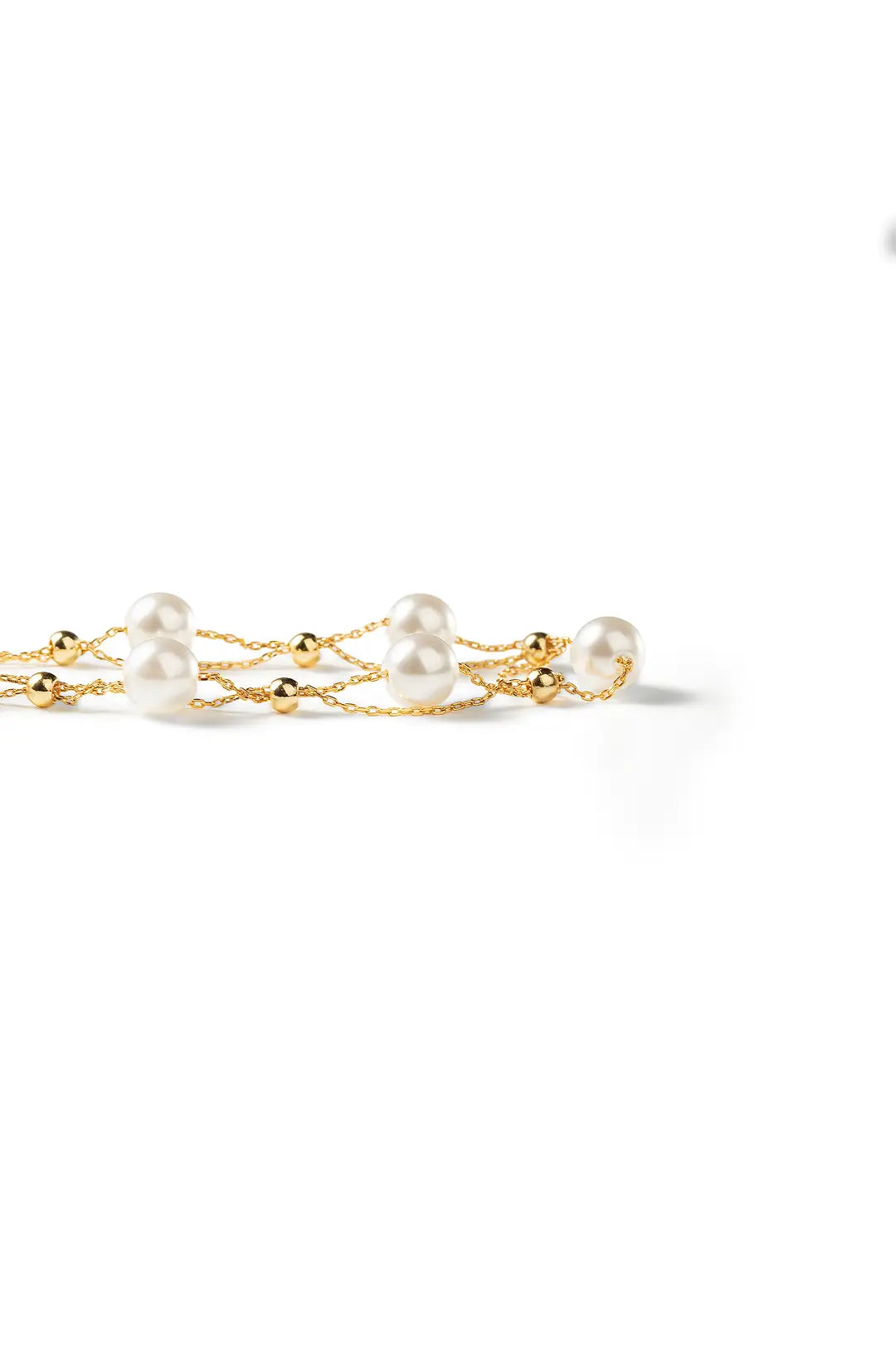 Aiko Tanaka Tsuzuri bracelet laid flat, a gold chain dotted with small white pearls, shown on a white background