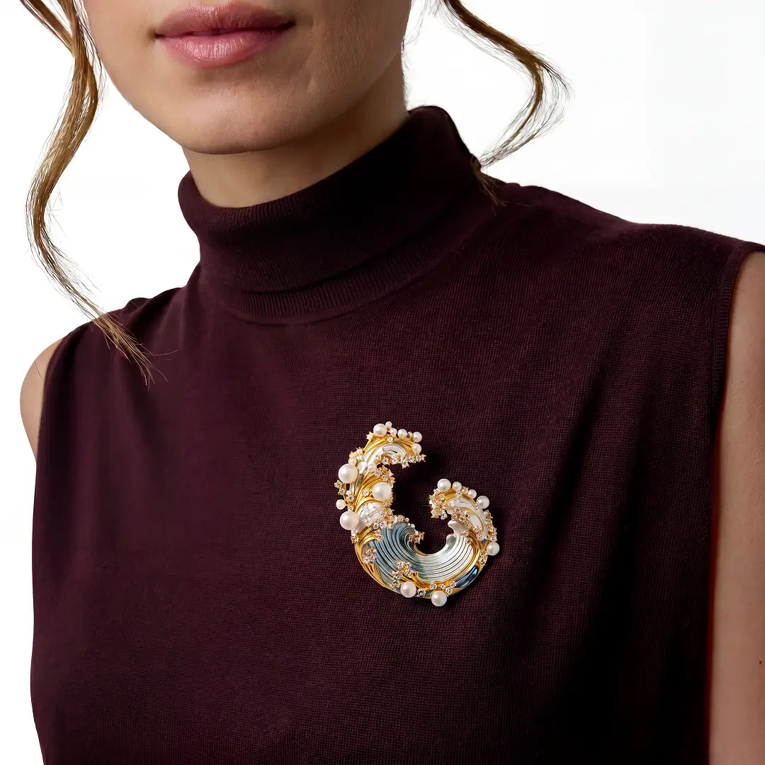 Woman in a burgundy sleeveless turtleneck wearing the Aiko Tanaka Shiosai no Wa gold wave brooch with pearls