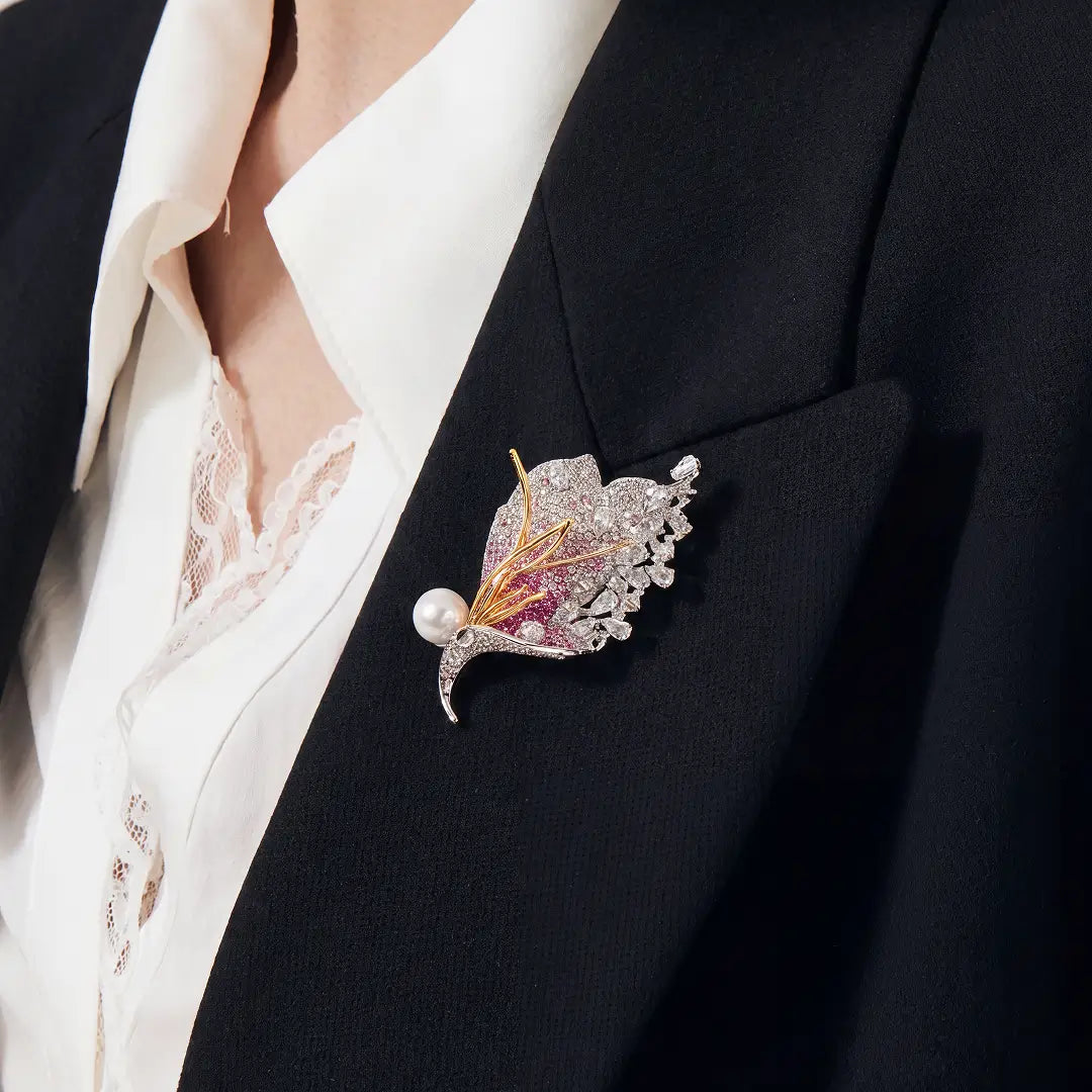 Aiko Tanaka Akatsubasa brooch, a pink crystal wing with a white pearl, pinned to a black blazer over a cream shirt