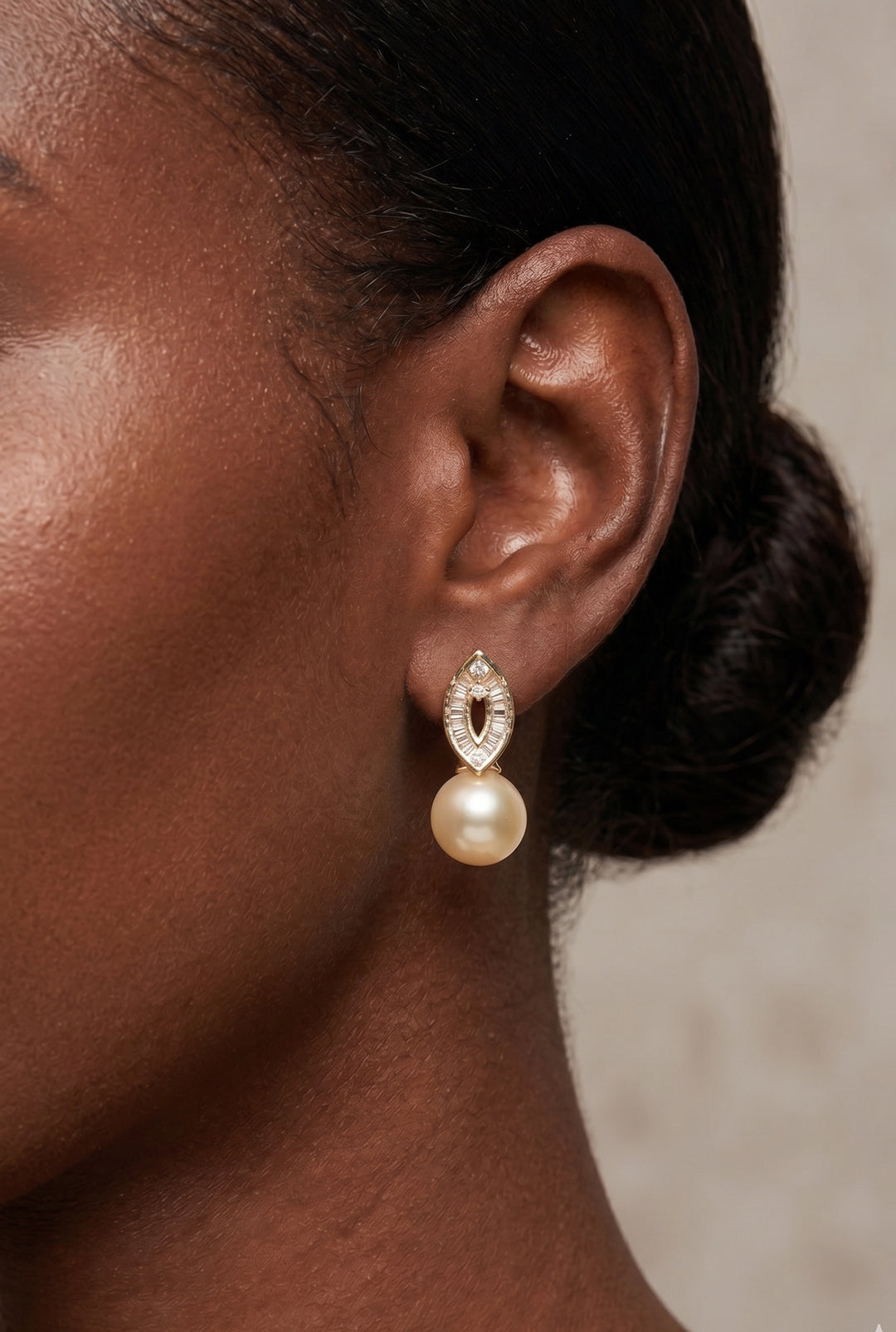 Close-up of a woman with a low bun wearing the Aiko Tanaka Aurelia Trace gold crystal earring with a peach pearl drop