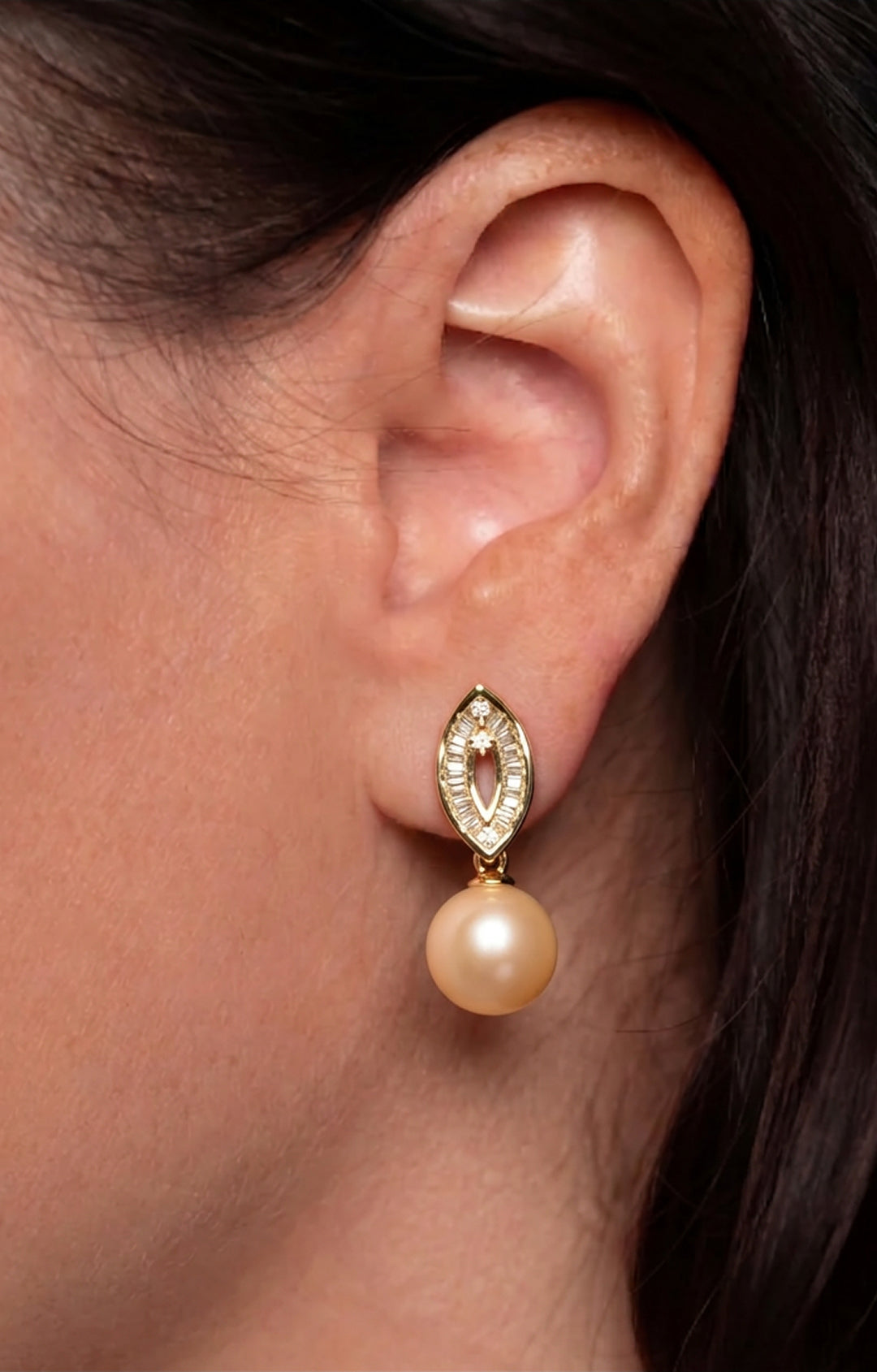 Ear wearing the Aiko Tanaka Aurelia Trace drop earring, a gold crystal marquise with a golden peach pearl below