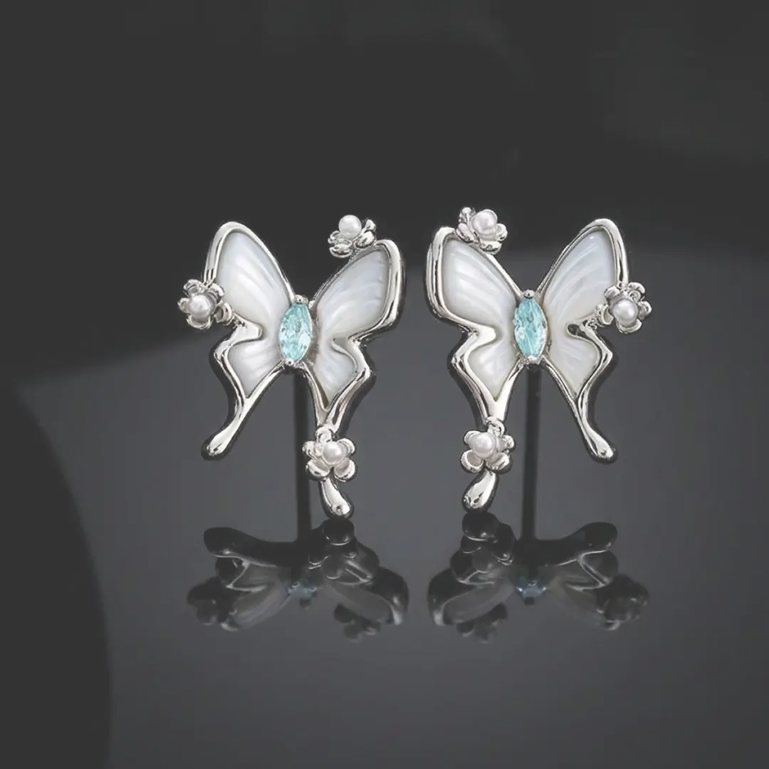 Aiko Tanaka Hakuyo earrings, mother-of-pearl butterflies with blue stones and pearls, displayed on black