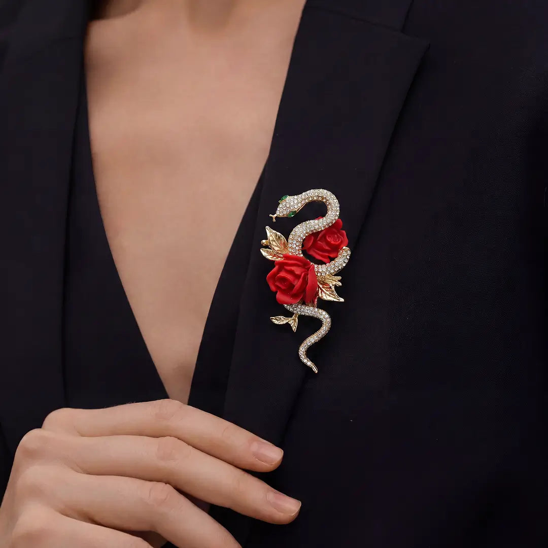 Aiko Tanaka Hebi no Chigiri brooch, a gold snake and red rose design, pinned to the lapel of a black blazer