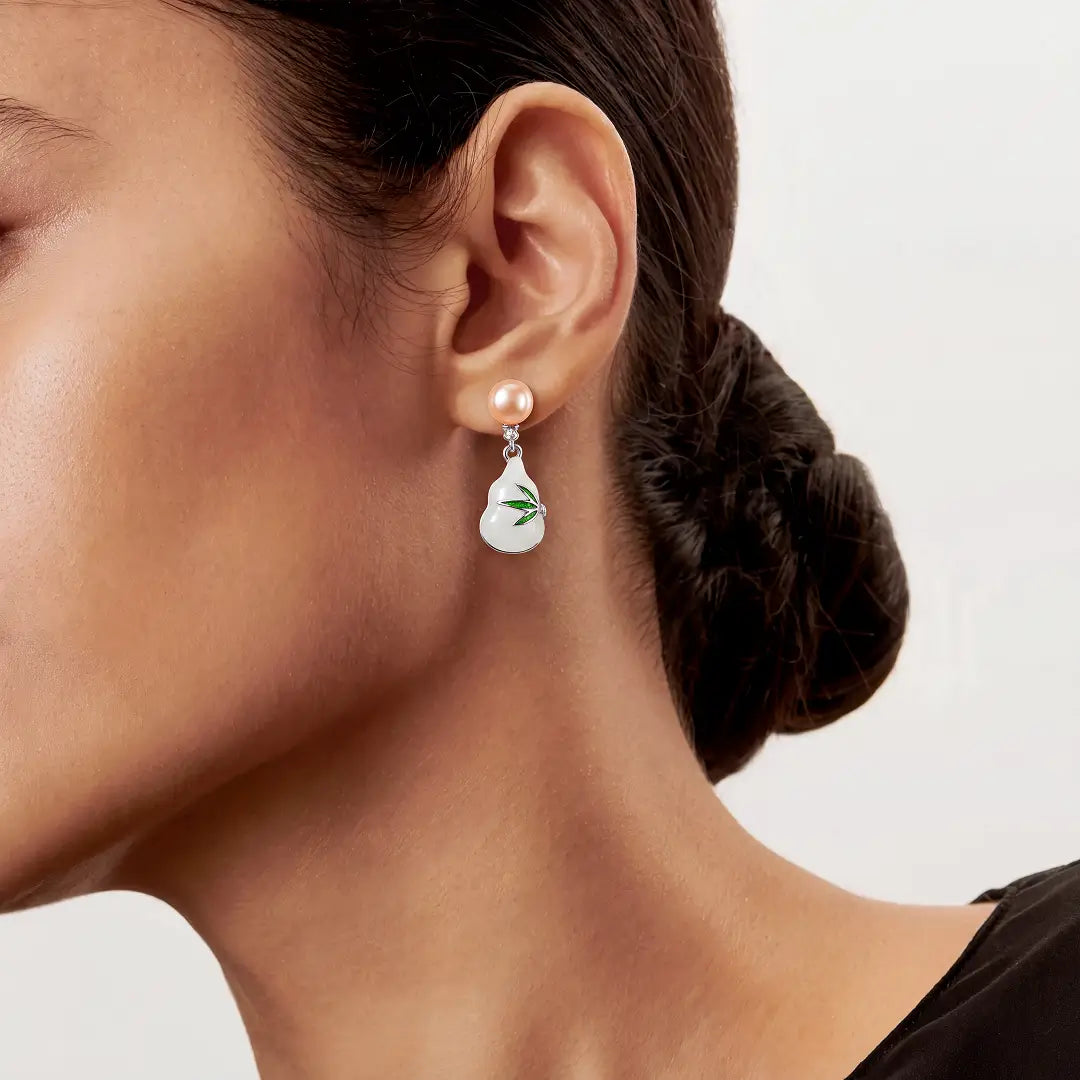 Aiko Tanaka Hisui no Mi earrings worn with hair in a low bun, a white enamel gourd drop with a green leaf