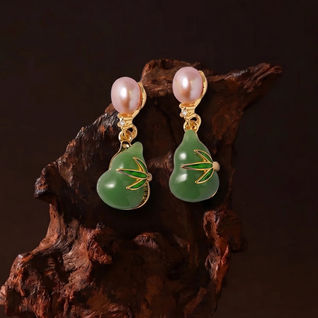 Aiko Tanaka Hisui no Mi green jade gourd earrings with pink pearls hanging on dark carved wood