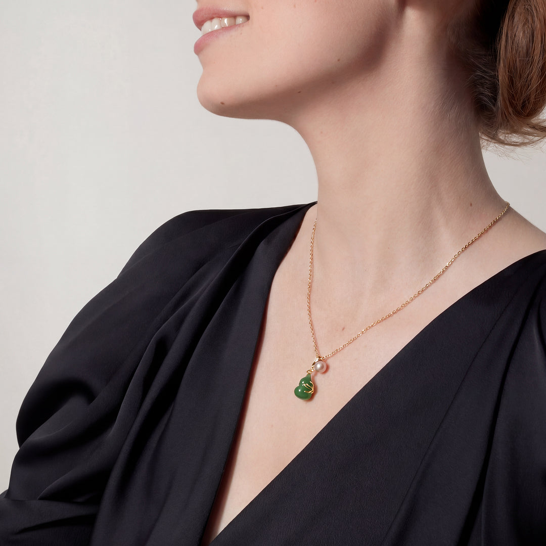 Woman in a black top wearing the Aiko Tanaka Tsuyu no Kakera gold chain necklace with a small jade gourd pendant