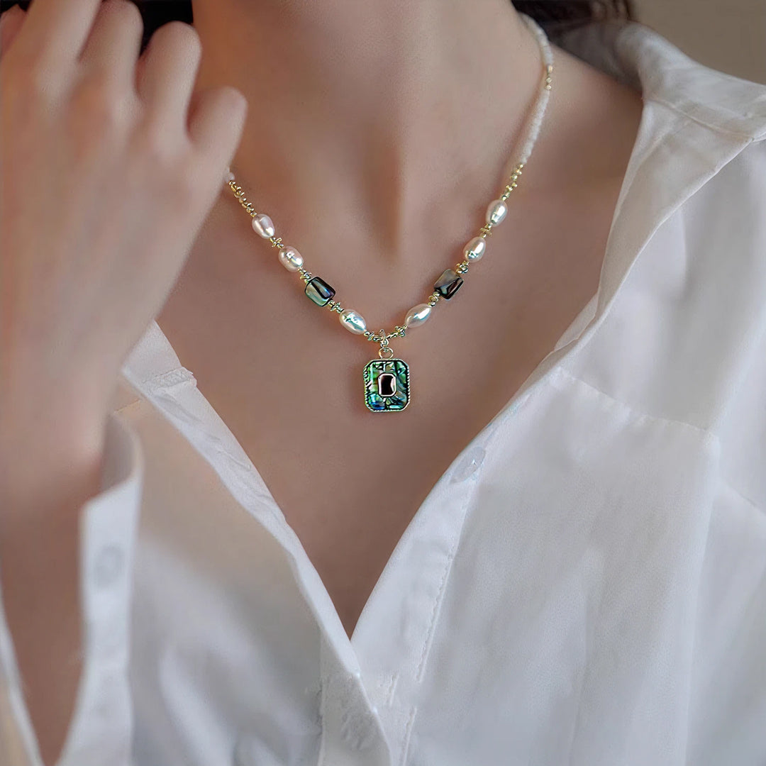 Woman touching her collar in a white shirt, wearing the Aiko Tanaka Kai no Hoseki pearl necklace with abalone pendant