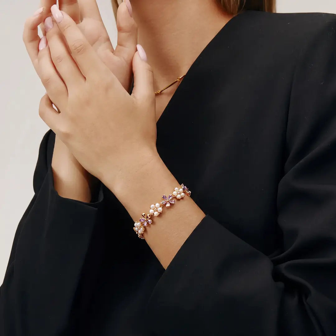 Aiko Tanaka Kasen bracelet, a pink flower and pearl chain bracelet, worn on the wrist with a black blazer