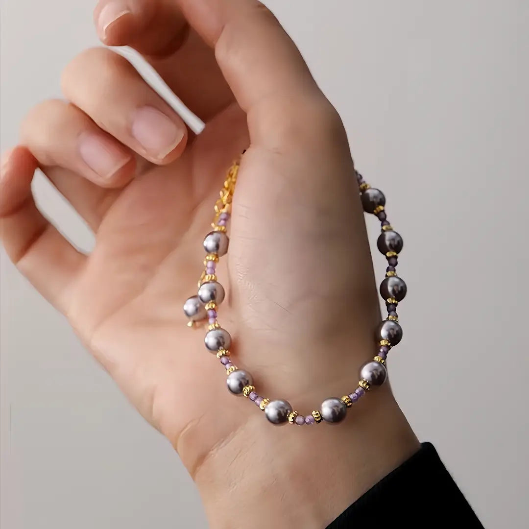 Aiko Tanaka Kasumi no Ito bracelet, grey pearls spaced on a fine gold chain, worn on the wrist with a black sleeve