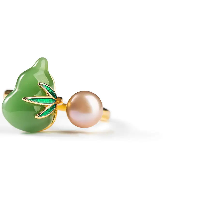 Close-up of the Aiko Tanaka Kissho ring showing its carved jade gourd and lustrous pink pearl, on white