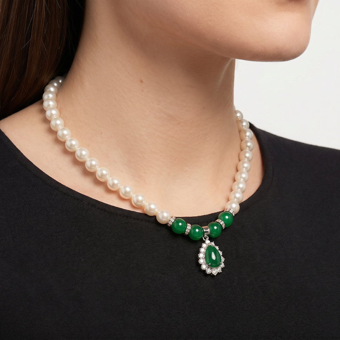 Woman in a black top wearing the Aiko Tanaka Kokei white pearl necklace with green beads and a green teardrop pendant