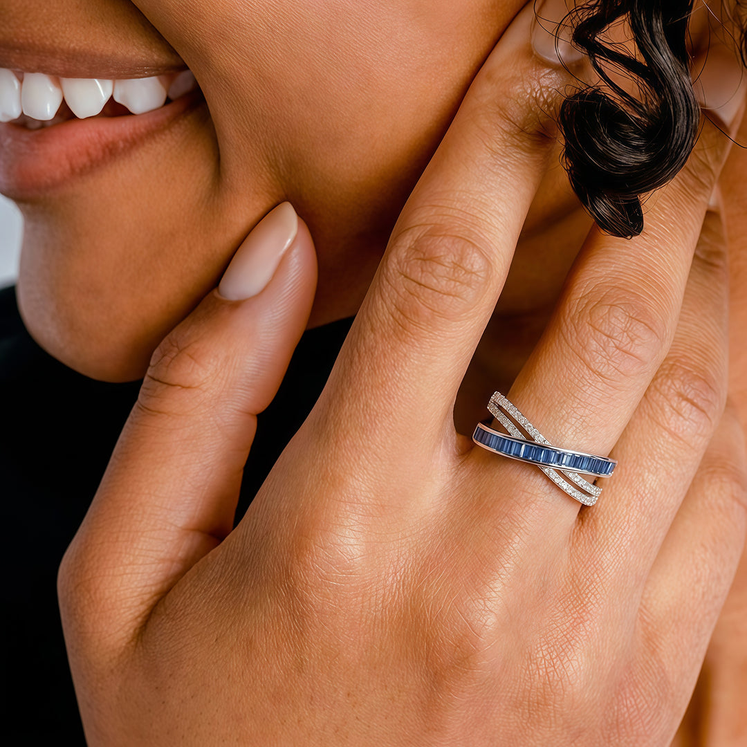 Close-up of a smiling woman's hand wearing the Aiko Tanaka Kosa crossover ring with blue and pink stones
