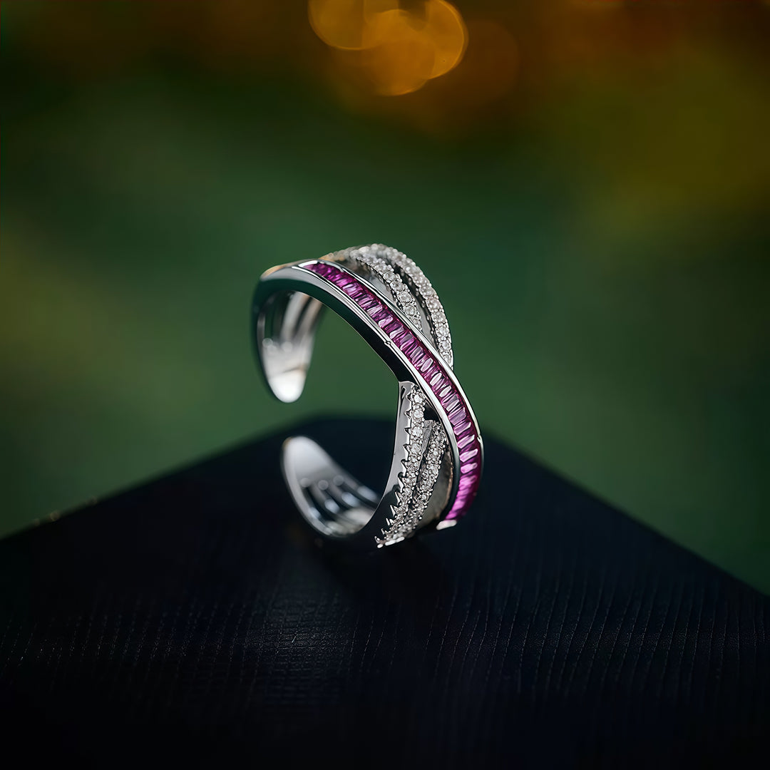 Aiko Tanaka Kosa crossover ring with pink and white crystals on a dark surface with warm green and gold bokeh