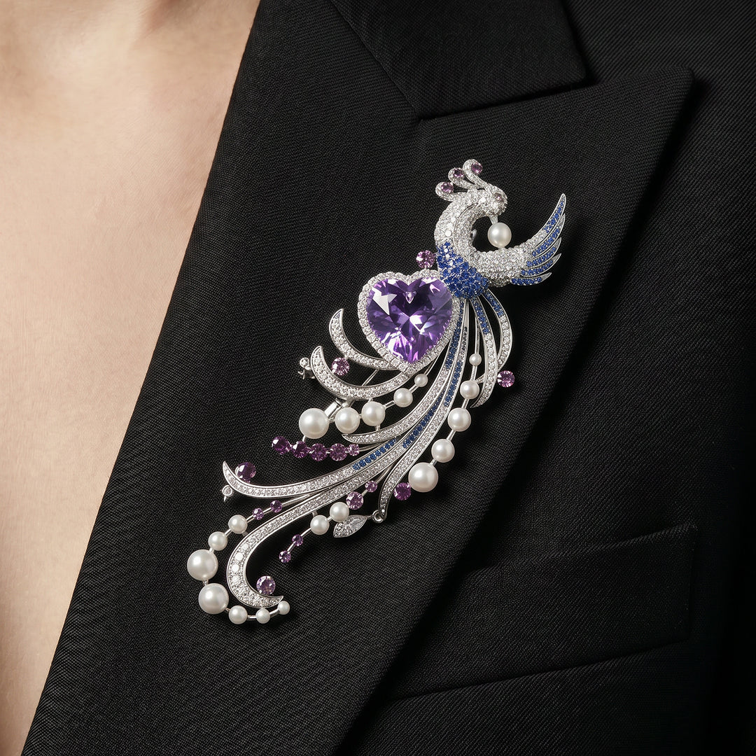 Black blazer lapel wearing the Aiko Tanaka Kujaku no Shingetsu peacock brooch with lilac heart stone and pearl tail