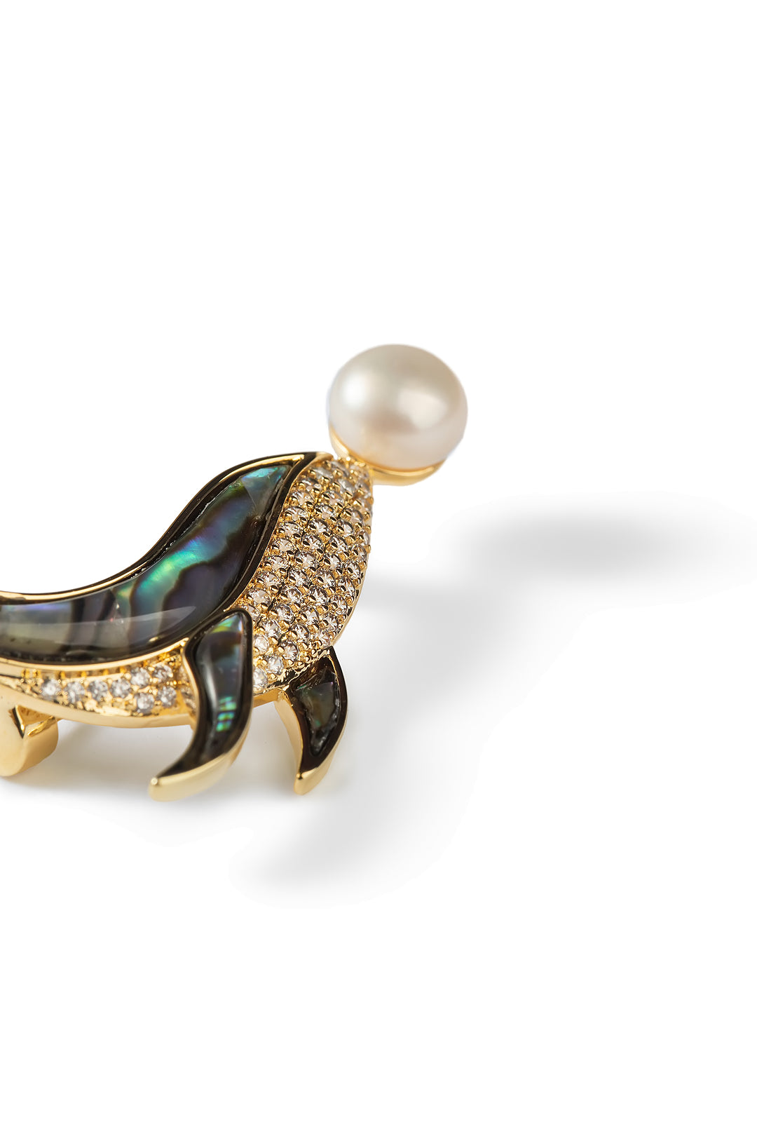 Side view of the Aiko Tanaka Kujira no Uta whale brooch with an abalone body and a pink-white pearl, on white