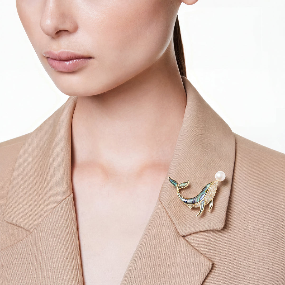 Woman in a beige blazer wearing the Aiko Tanaka Kujira no Uta whale brooch with a pearl on her lapel
