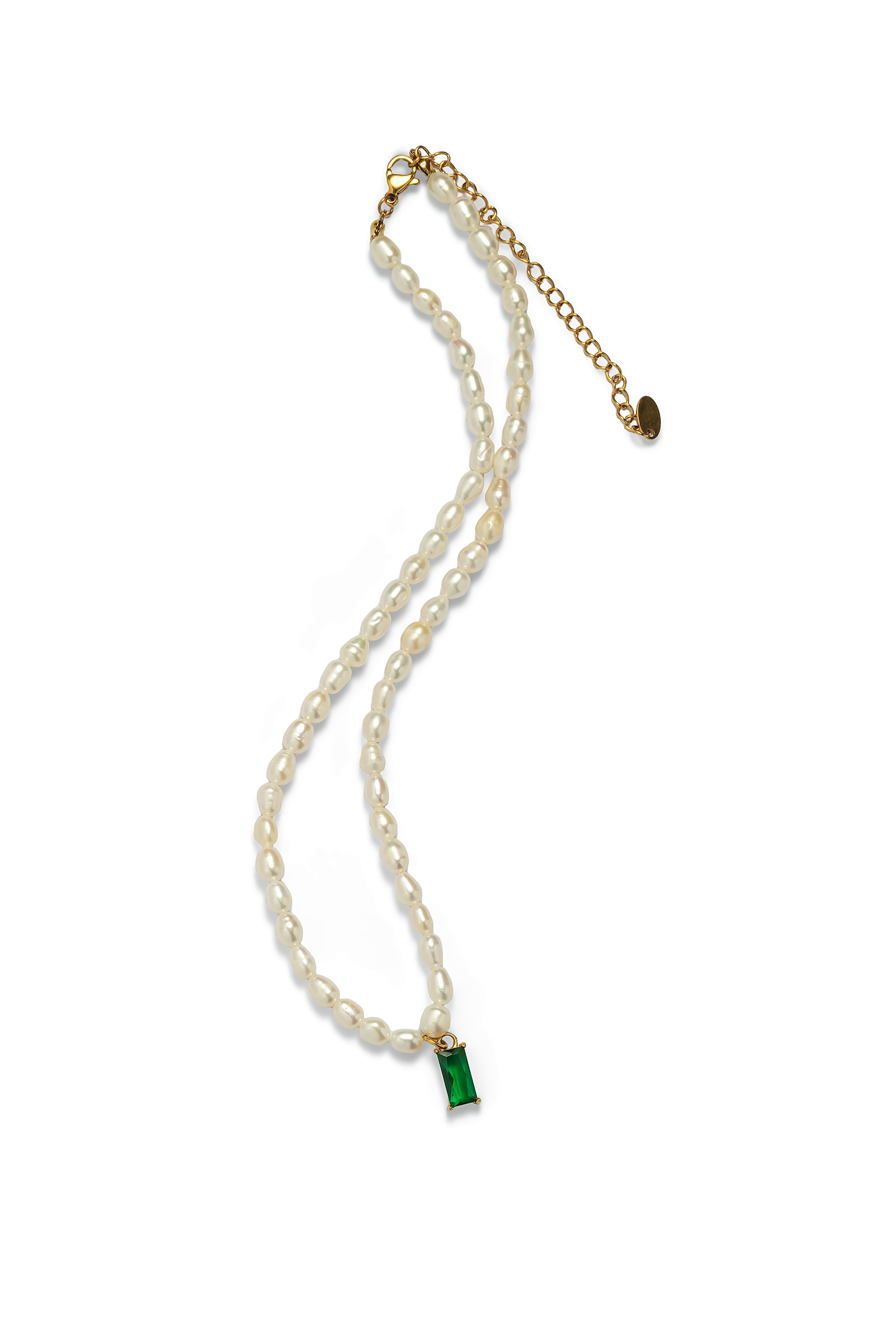 Aiko Tanaka Midori no Hazama rice pearl necklace with a green emerald-cut pendant and gold clasp, laid flat on white