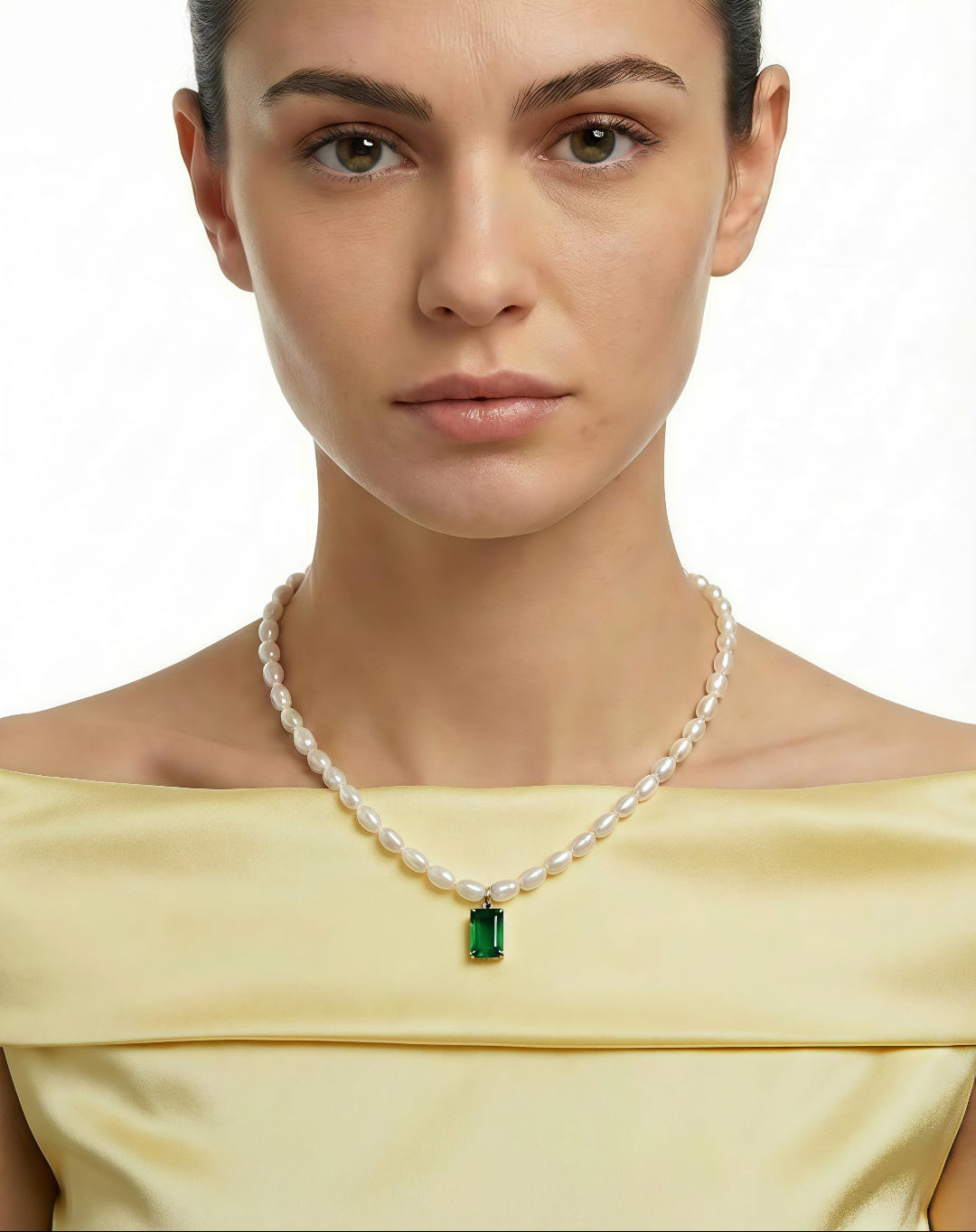 Woman in a yellow off-shoulder top wearing the Aiko Tanaka Midori no Hazama pearl necklace with a green stone pendant