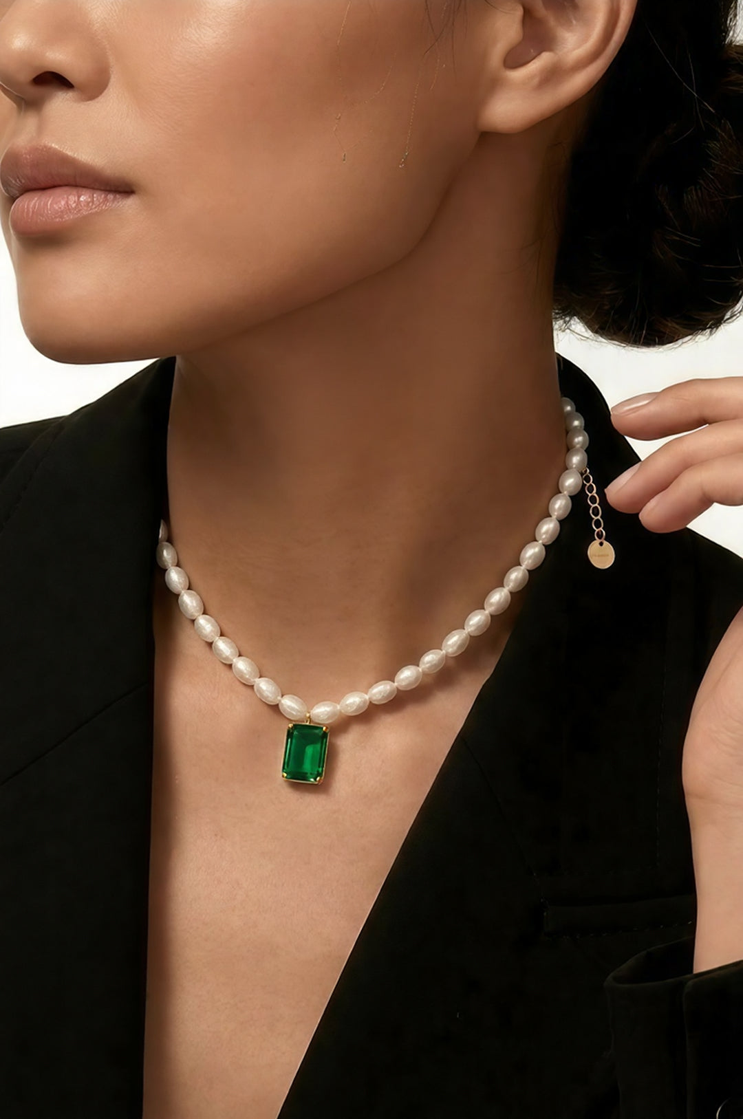 Side view of a woman in a black blazer wearing the Aiko Tanaka Midori no Hazama pearl necklace with a green stone drop