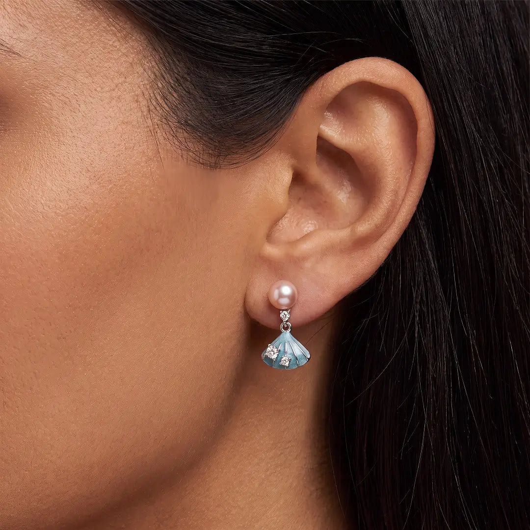 Aiko Tanaka Nagisa earring close-up on the ear, a peach pearl above a blue enamel shell-shaped drop