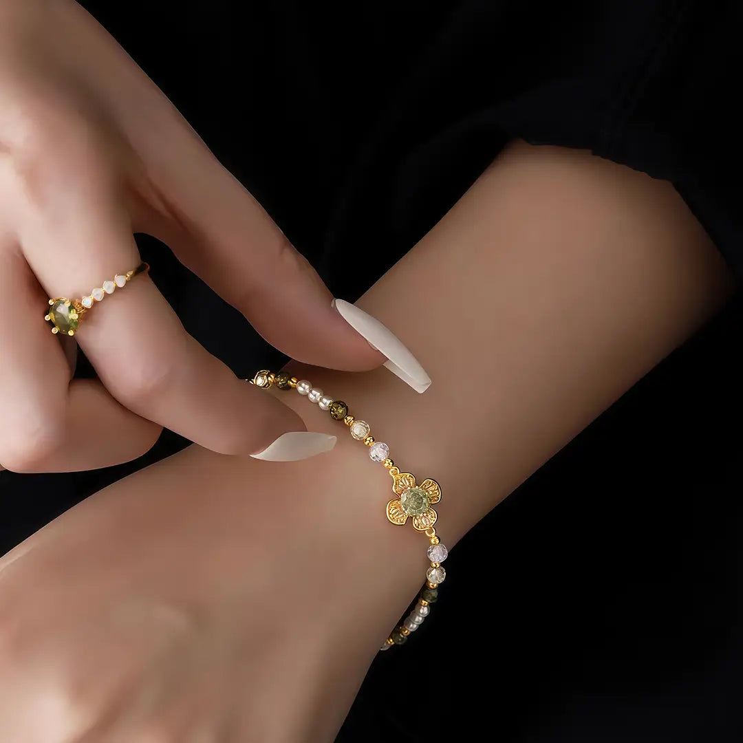 Aiko Tanaka Renka bracelet, a pearl and gold flower bracelet on the wrist against black, with a gold ring