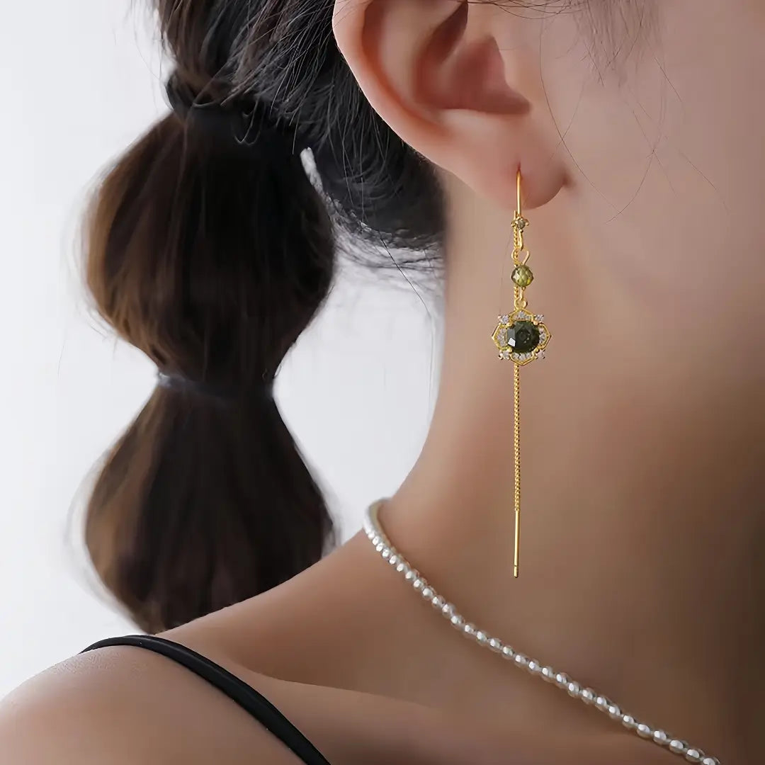 Aiko Tanaka Rensui earrings, a gold threader with a green stone flower charm, worn with a seed pearl necklace
