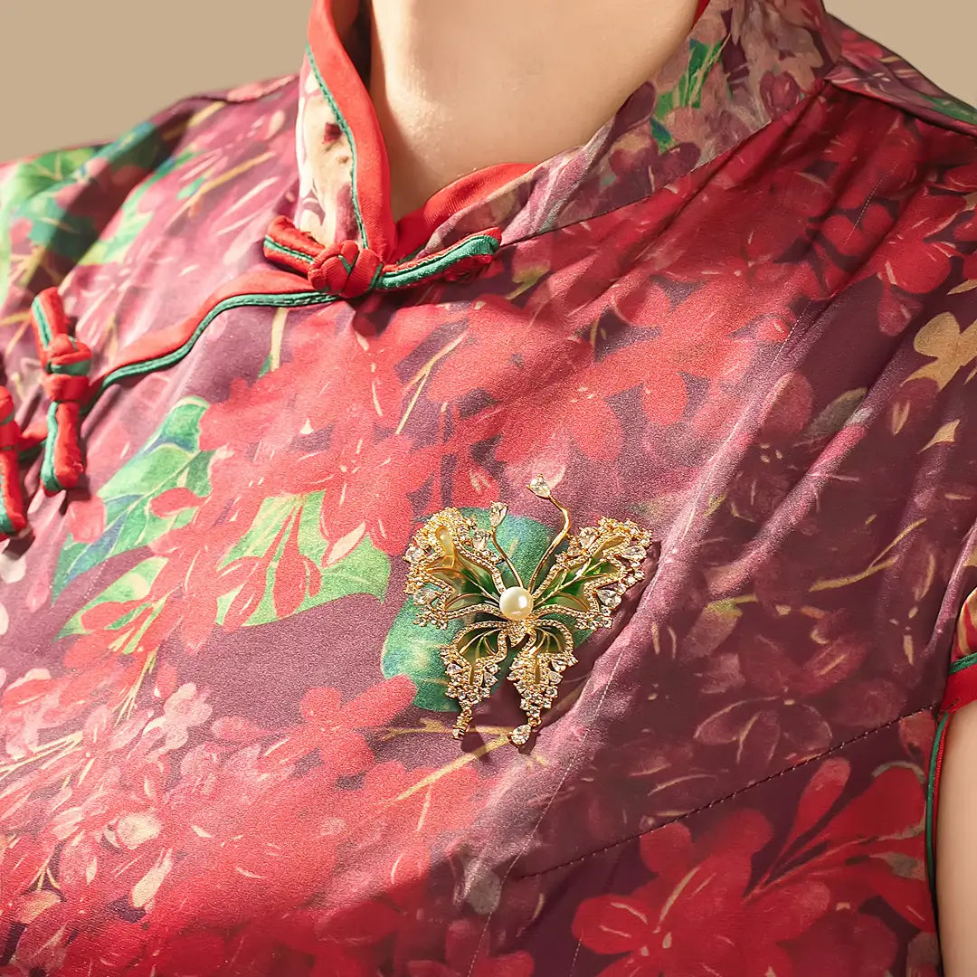 Woman in a red floral qipao wearing the Aiko Tanaka Ryokucho no Mai green enamel butterfly brooch