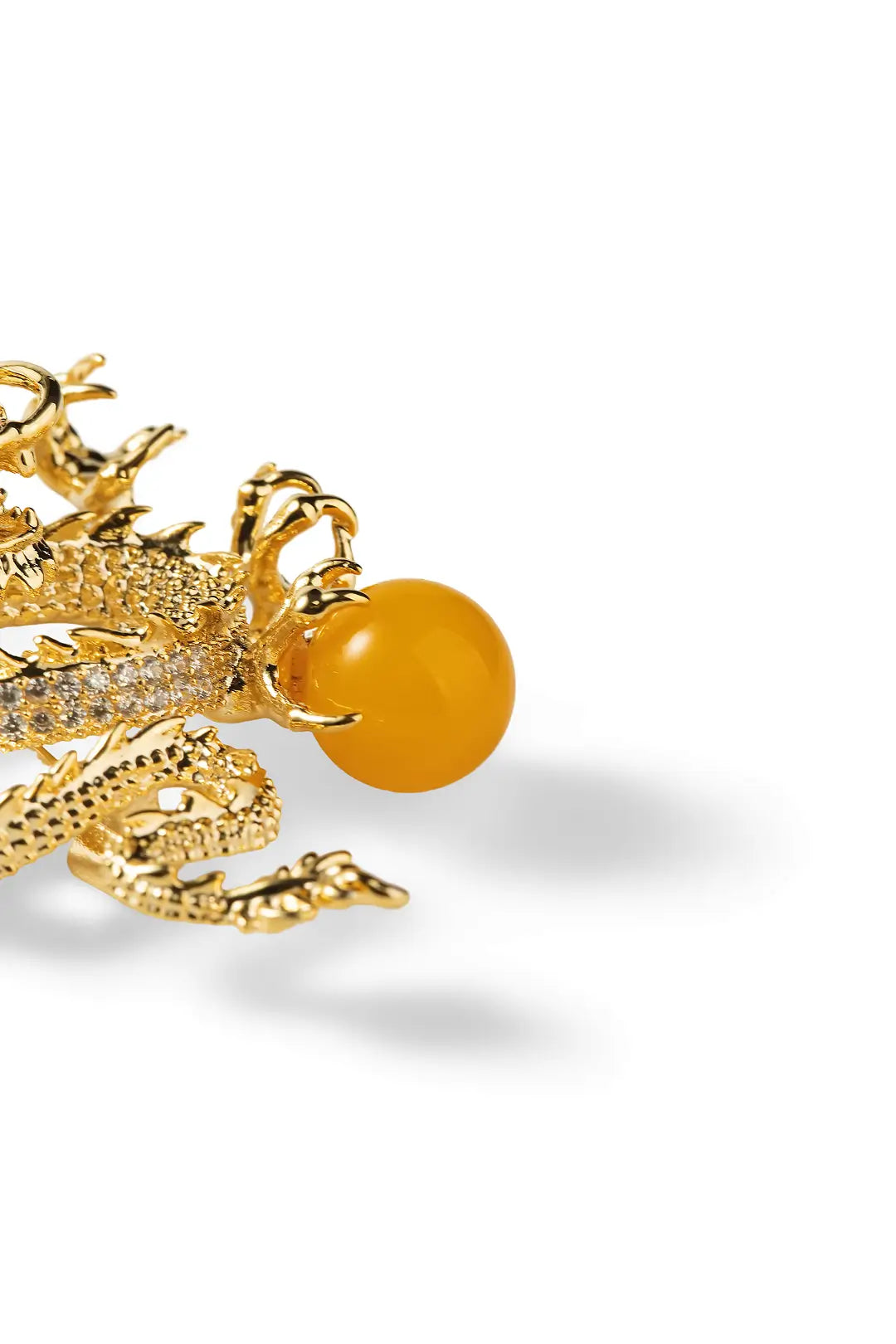 Aiko Tanaka Ryuko brooch close-up showing the gold dragon's crystal-set scales and amber orb on a white background