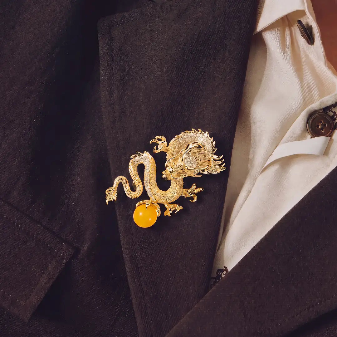 Aiko Tanaka Ryuko brooch, a gold crystal dragon with an amber orb, pinned to a dark blazer over a cream shirt