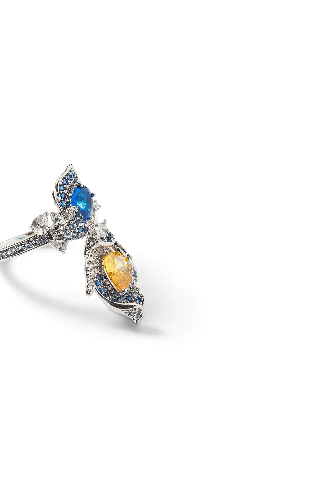Side view of the Aiko Tanaka Seiran no Mai ring with blue and yellow stones in a silver floral setting, on white