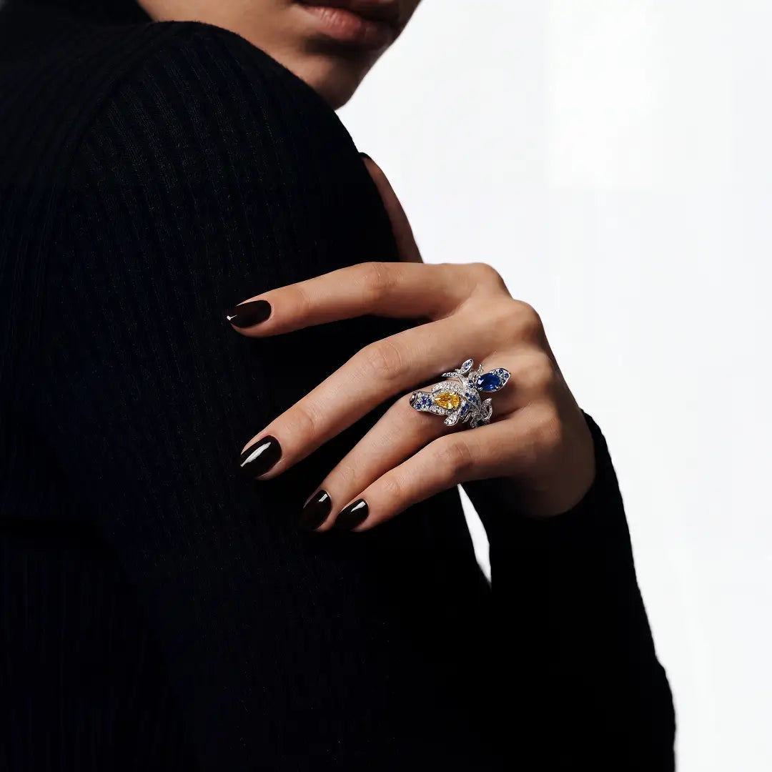 Hand with dark nail polish resting on a black sleeve wearing the Aiko Tanaka Seiran no Mai blue stone ring