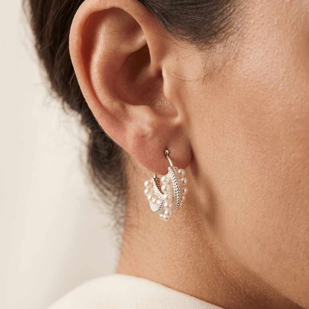 Aiko Tanaka Shiranami earrings, a silver crystal and pearl hoop, worn on the ear of a model with hair pulled back