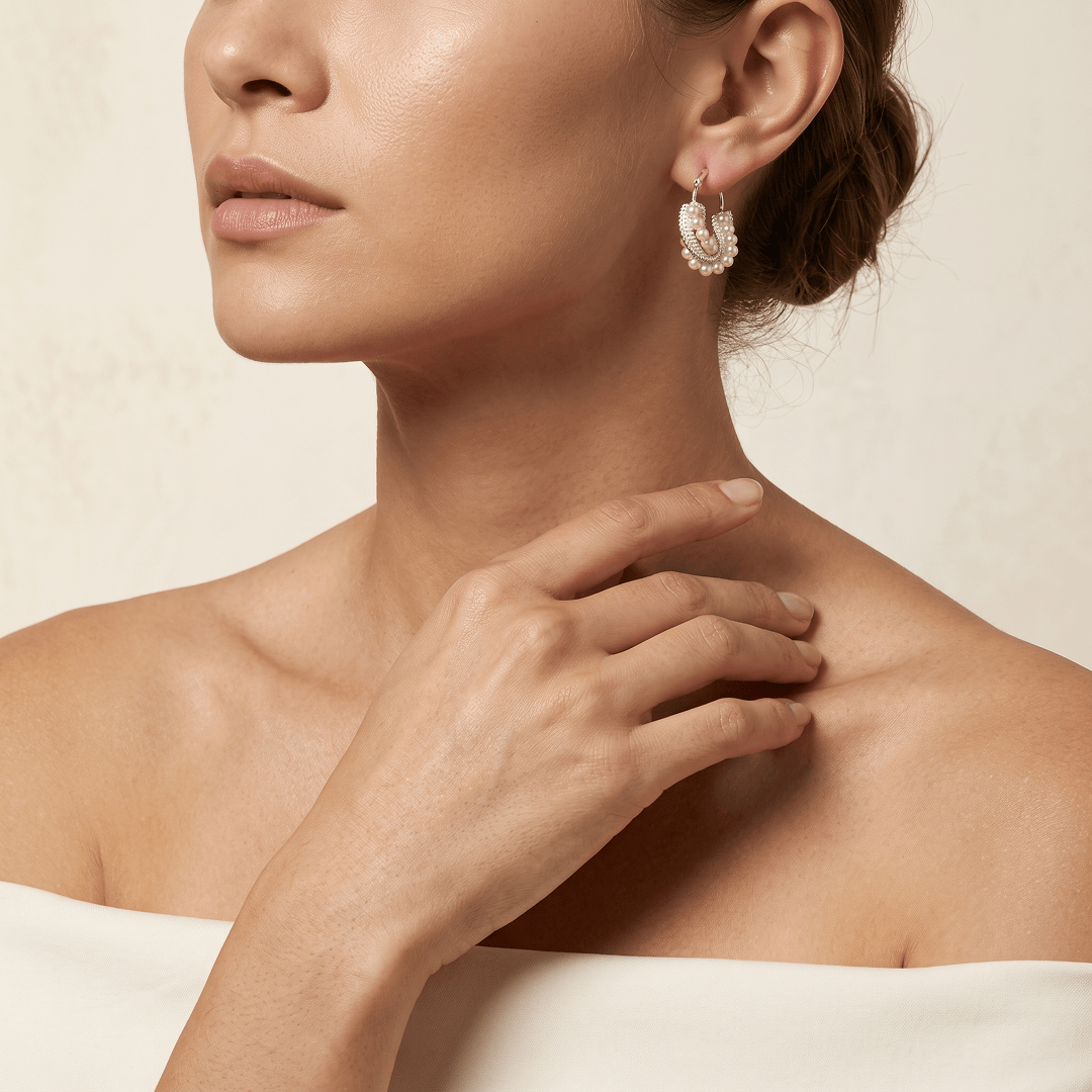 Aiko Tanaka Shiranami earrings, a silver pearl hoop, worn by a model with hand at the collarbone and bare shoulders