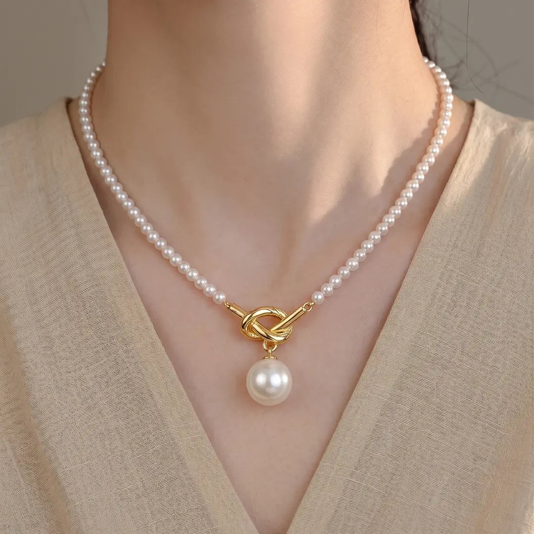 Woman in a beige knit wearing the Aiko Tanaka Shizuku no Chigiri pearl necklace with a gold clasp and pearl drop