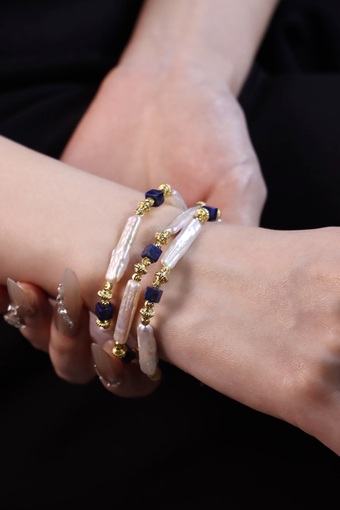 Crossed arms wearing the Aiko Tanaka Shizuku no Kage strand wrapped as a bracelet of stick pearls and navy cubes