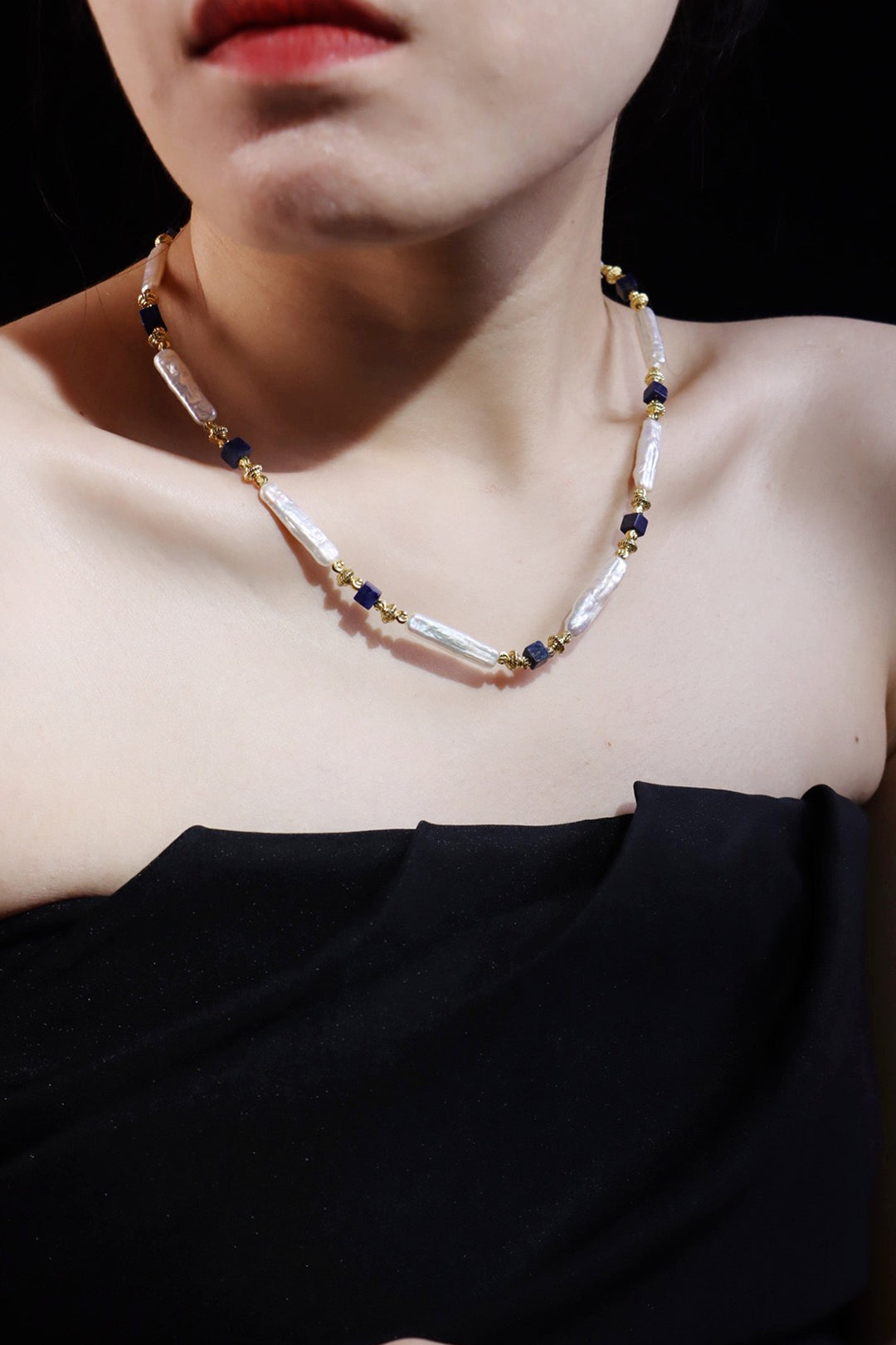 Woman in a black strapless top wearing the Aiko Tanaka Shizuku no Kage white stick pearl necklace with navy beads