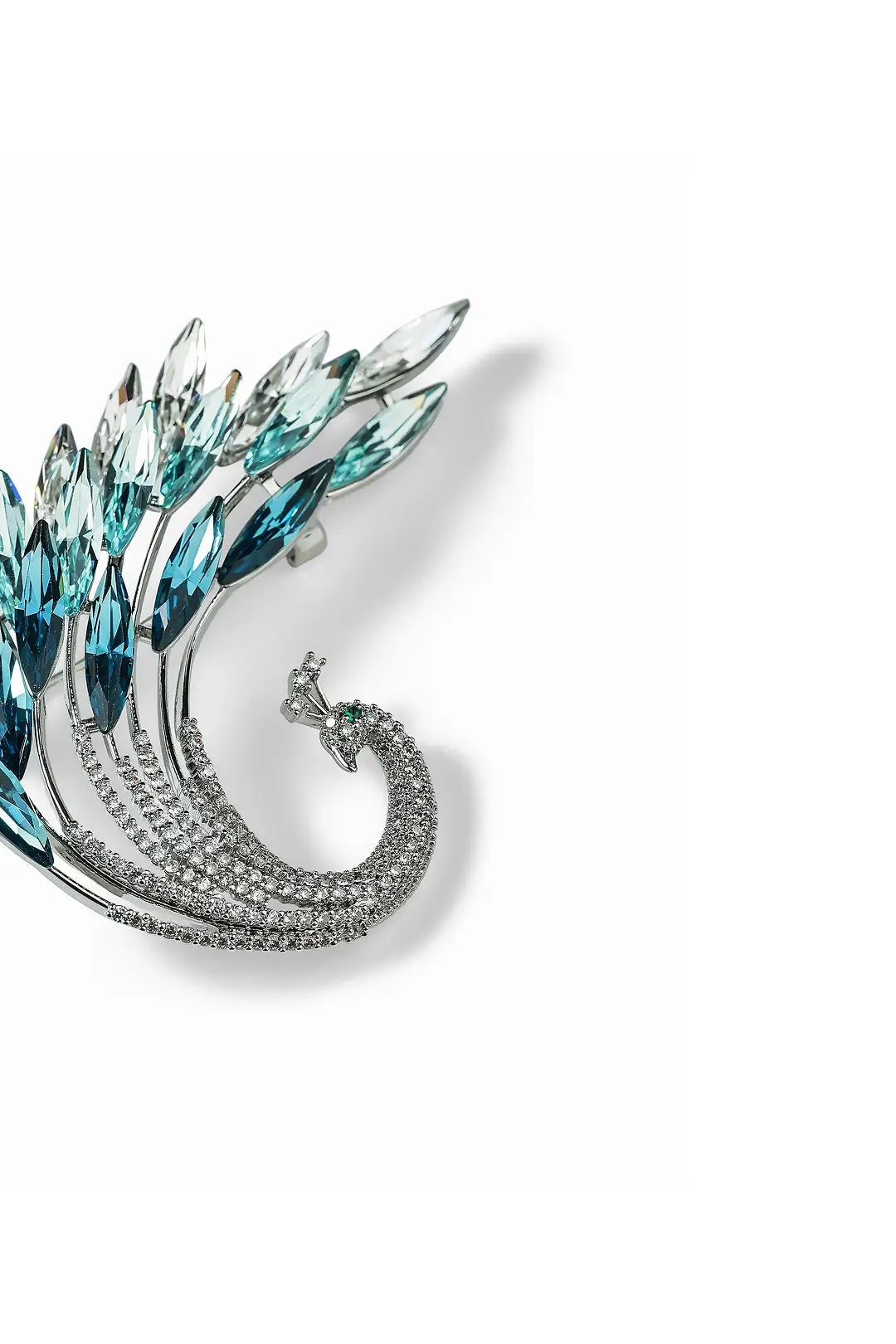 Aiko Tanaka Suibi brooch close-up, a silver peacock feather with teal crystal fronds, on a white background