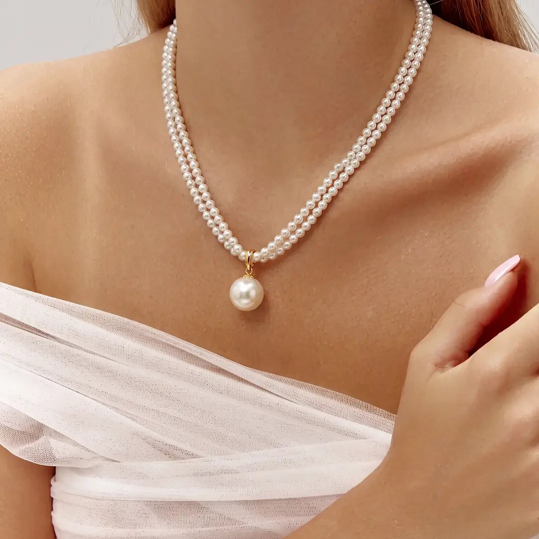 Aiko Tanaka Tsukishiro necklace, a double strand of small white pearls with a large pearl drop, worn by a model
