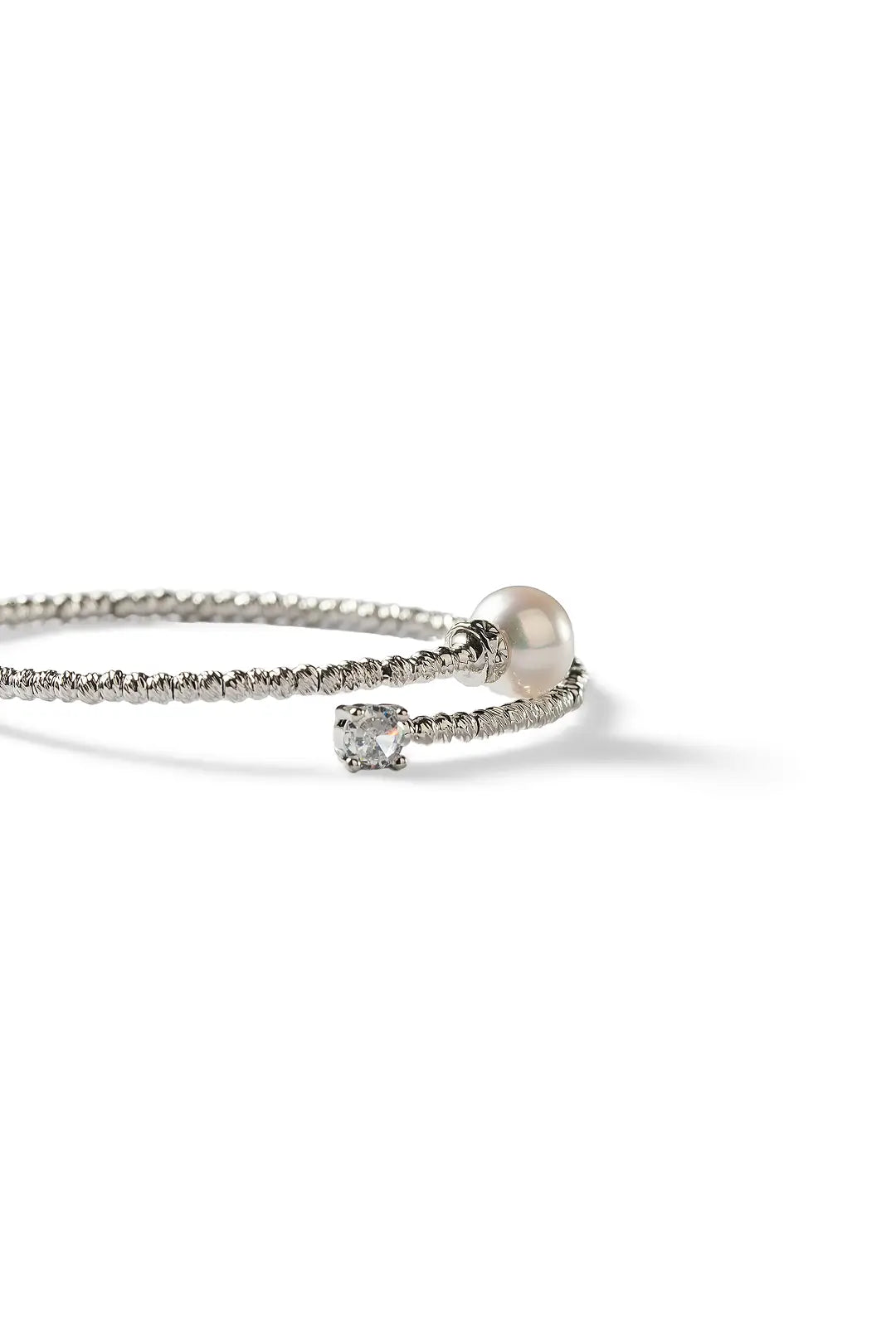 Aiko Tanaka Tsunagu bracelet, a silver crystal open cuff with a pearl and a clear stone, on a white background