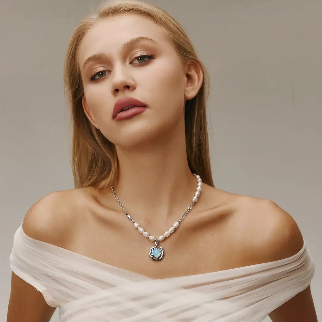 Aiko Tanaka Ukifune necklace, a pearl strand with a blue moonstone pendant, worn by a model in an off-shoulder top