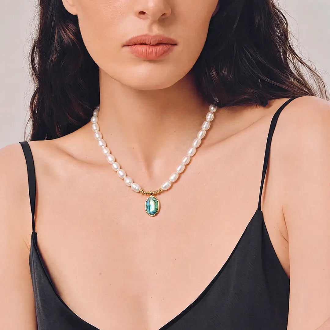 Aiko Tanaka Utsuro necklace, white freshwater pearls with an oval teal pendant, worn by a model in black