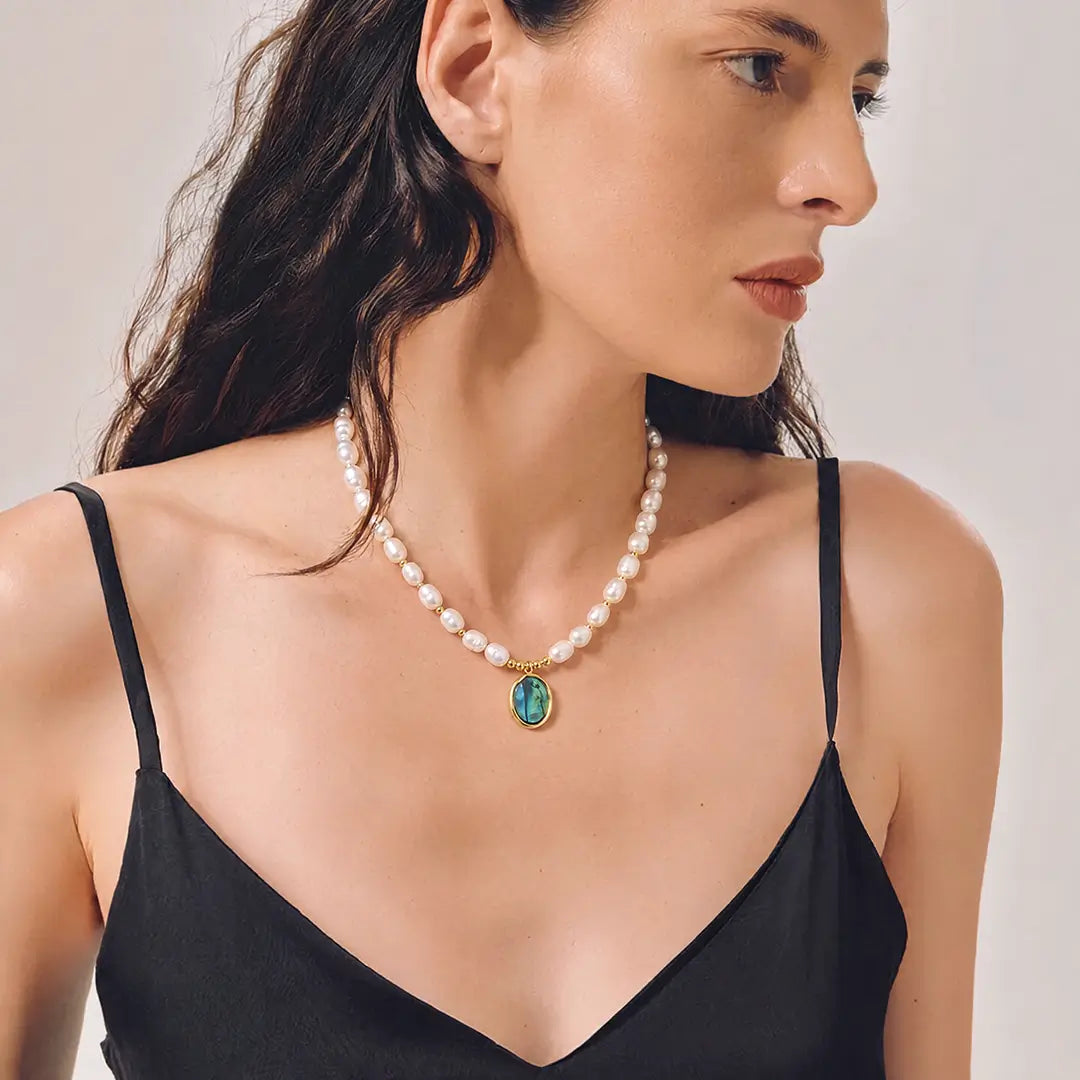 Aiko Tanaka Utsuro necklace, a freshwater pearl strand with a teal stone pendant, worn with a black camisole