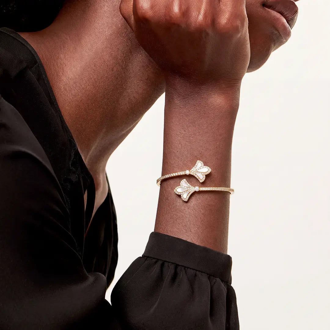 Aiko Tanaka Yohaku bracelet, a gold ginkgo leaf cuff worn on the wrist of a model in a dark top